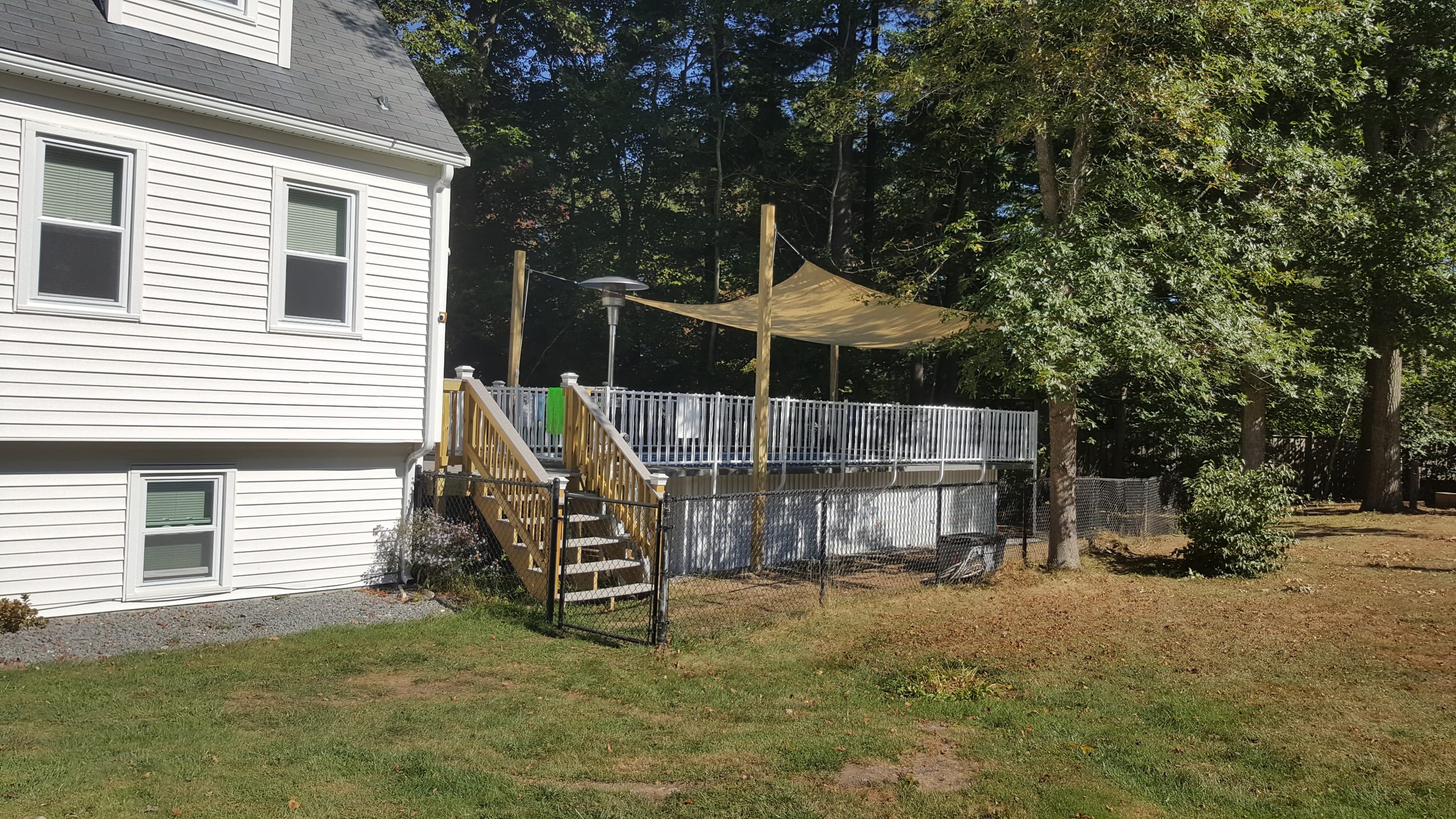 driveway view of above ground pool with deck and fence