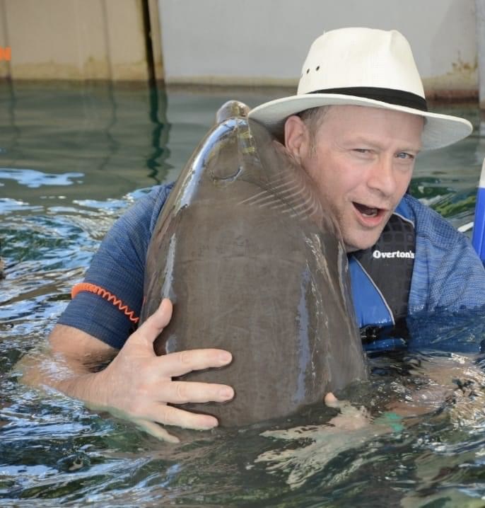 Mike the owner of MGK Pools get hugged by a dolphin
