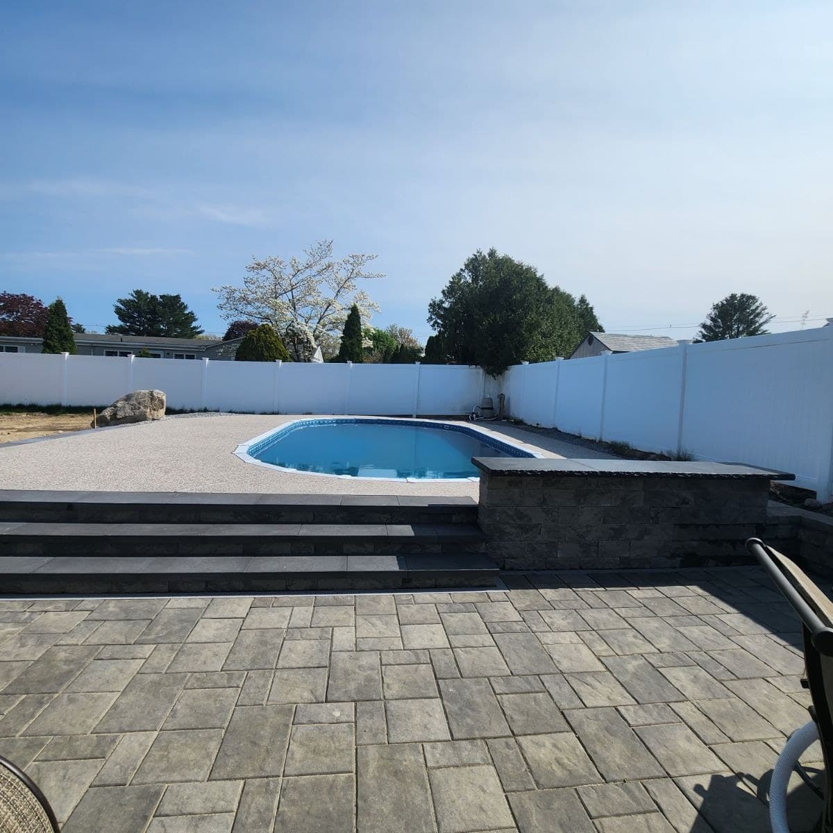 Aquasport 52 oval installed fully inground with a paver patio and vinyl fence - MGK Pools Inc Aquasport 52 oval installed fully inground with a paver patio and vinyl fence